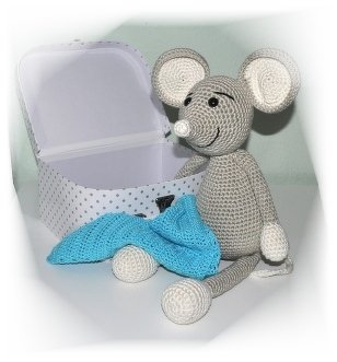 Graue-weiße Amigurumi-Maus sitzt neben einem blauen Häkelteil und einer offenen weißen Schachtel mit Punkten.