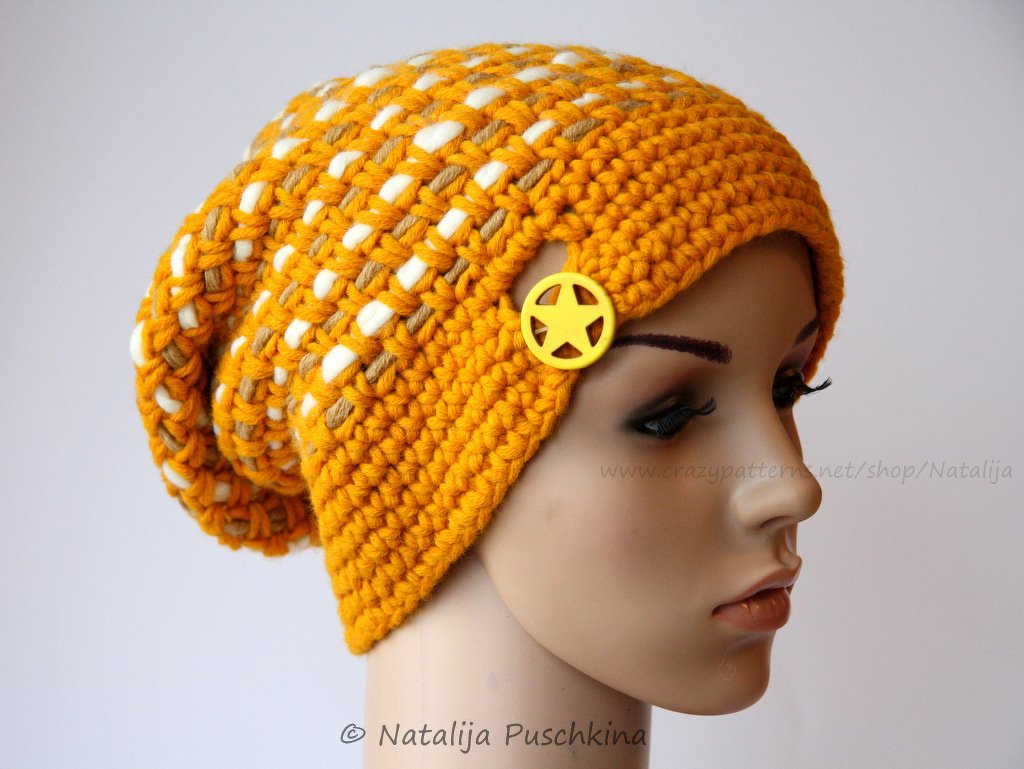 Gehäkelte senfgelbe Slouch‑Beanie mit weißen Einzügen und gelbem Sternknopf an Schaufensterkopf