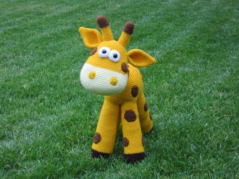 Gehäkelte gelbe Giraffe Amigurumi mit braunen Flecken auf Gras