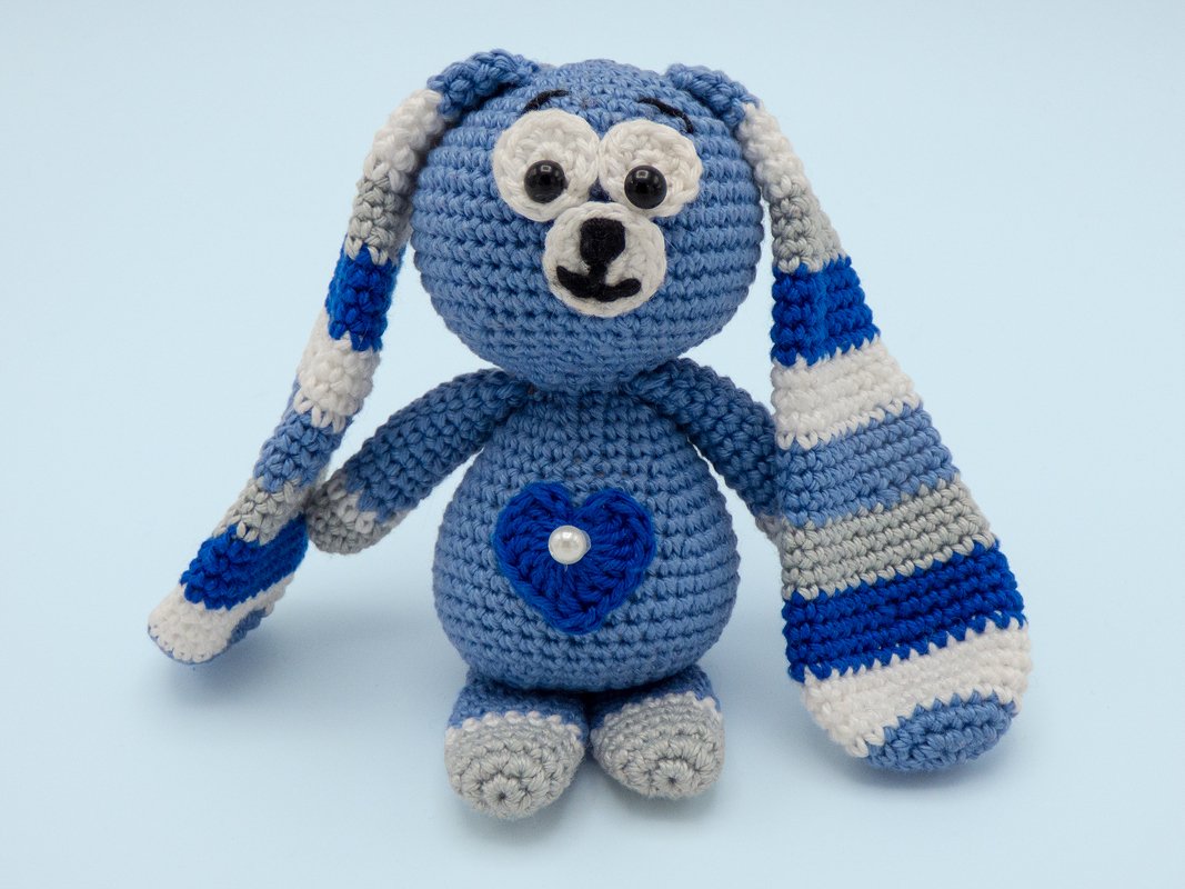Gehäkelter blauer Amigurumi-Hase mit gestreiften Ohren und Herzapplikation