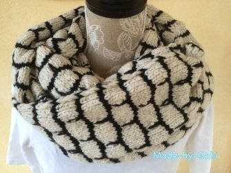 Zweifarbiger gestrickter Loop-Schal mit cremefarbener Basis und schwarzem Wabenmuster auf einer Büste