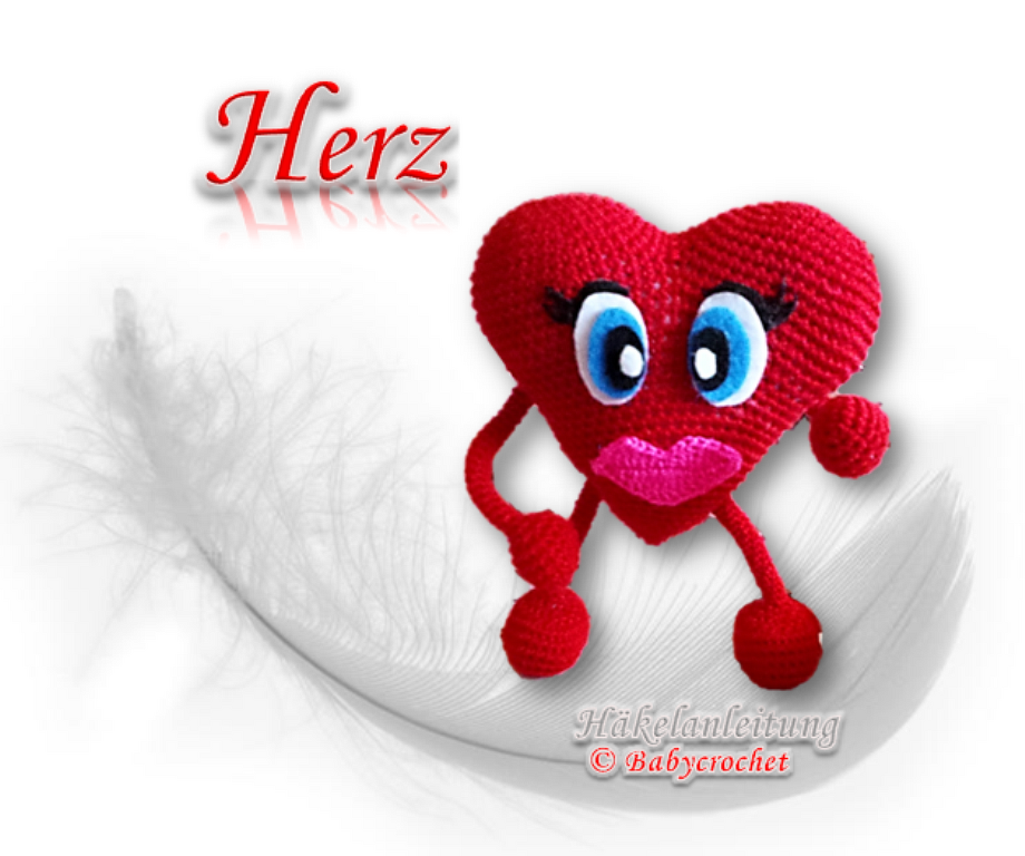 Rotes gehäkeltes Herz-Amigurumi mit Gesicht auf weißer Feder