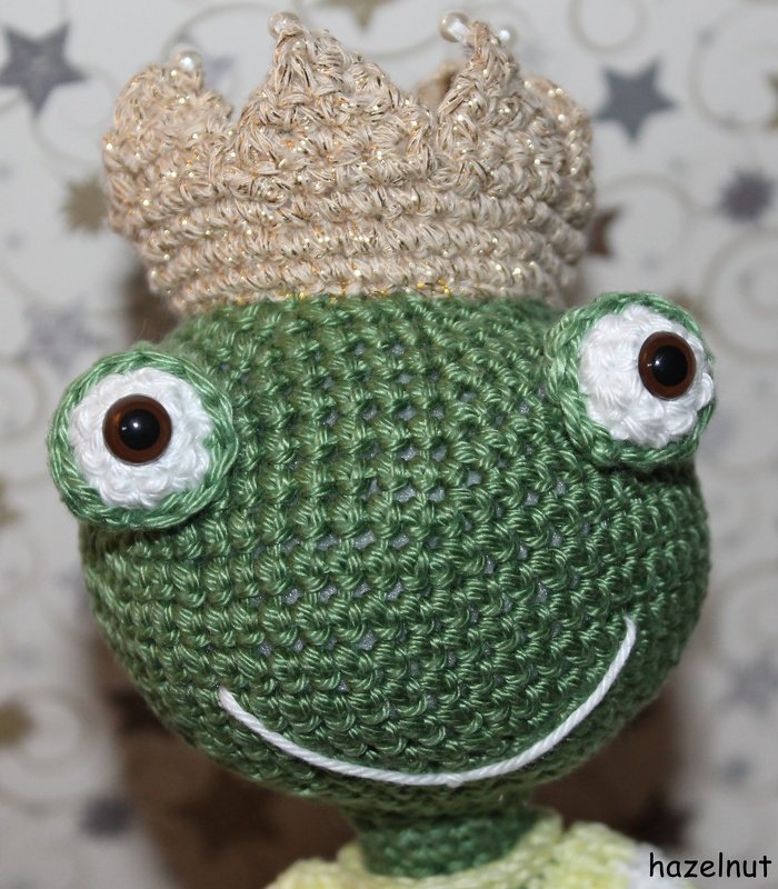 Grüner gehäkelter Frosch mit schimmernder Krone und großen Augen