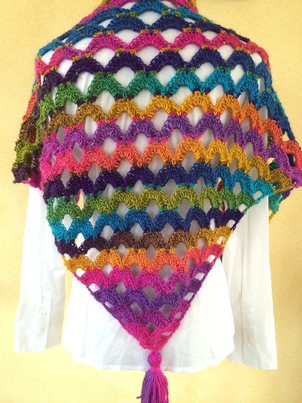 Buntes gehäkeltes Dreieckstuch mit Muschelmuster und Quaste über weißer Bluse