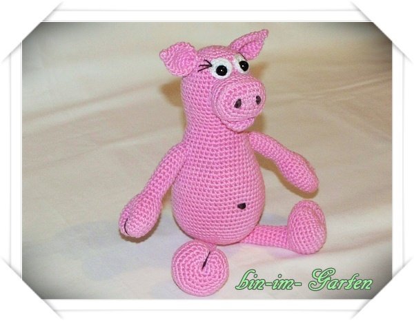 Gehäkeltes rosa Amigurumi‑Schwein, sitzend auf hellem Untergrund