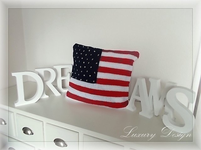 Quadratisches gestricktes Kissen mit US-Flaggenmuster auf weißer Kommode