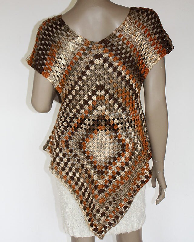 Gehäkelte Tunika aus Granny Squares in Braun, Beige und Orange mit V-Ausschnitt auf einer Schaufensterpuppe.