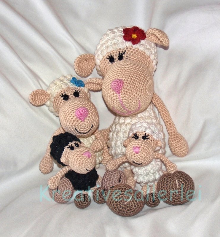 Vier gehäkelte Amigurumi-Schafe, drei weiße und ein schwarzes, auf hellem Hintergrund