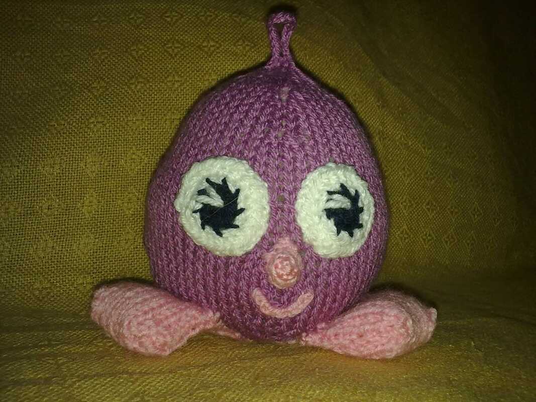 Gestricktes lila Amigurumi mit weißen Augen und rosafarbenen Füßen