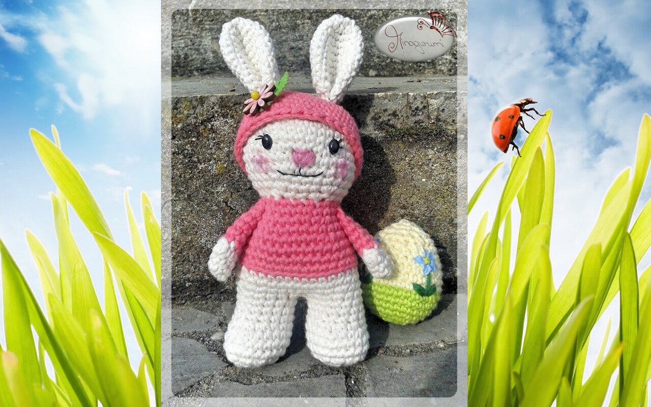 Gehäkelter weißer Hase mit rosa Kapuze und gehäkeltem Osterei