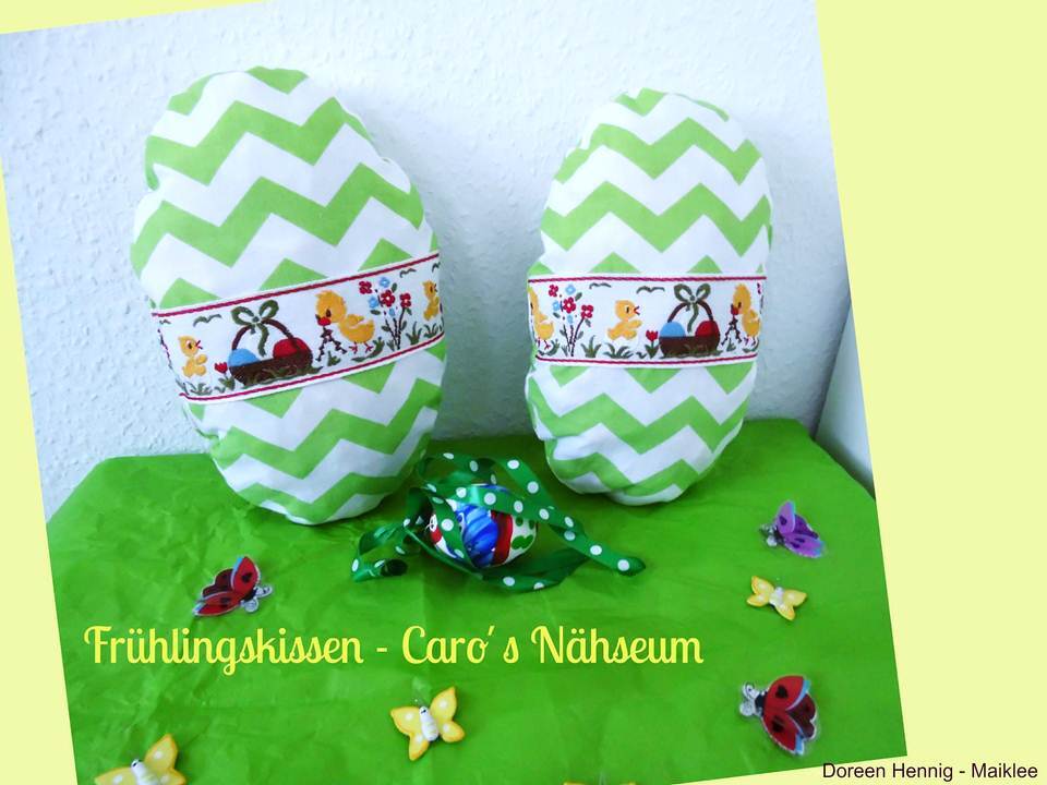 Zwei genähte ovale Kissen mit grün-weißem Zickzackstoff und Kükenbordüre