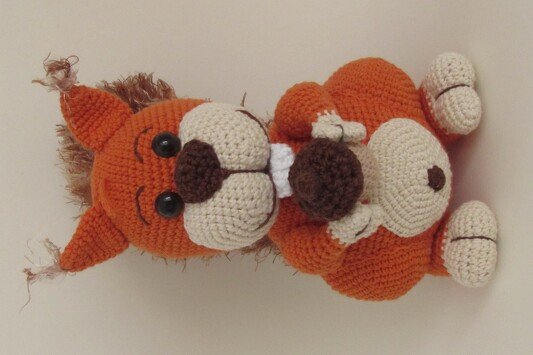 Orangefarbenes gehäkeltes Eichhörnchen-Amigurumi mit beigen Akzenten und brauner Eichel