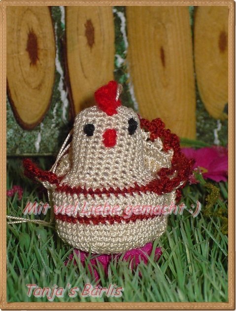 Nahaufnahme eines beigen Amigurumi‑Huhns mit rotem Kamm und Aufhängeschlaufe