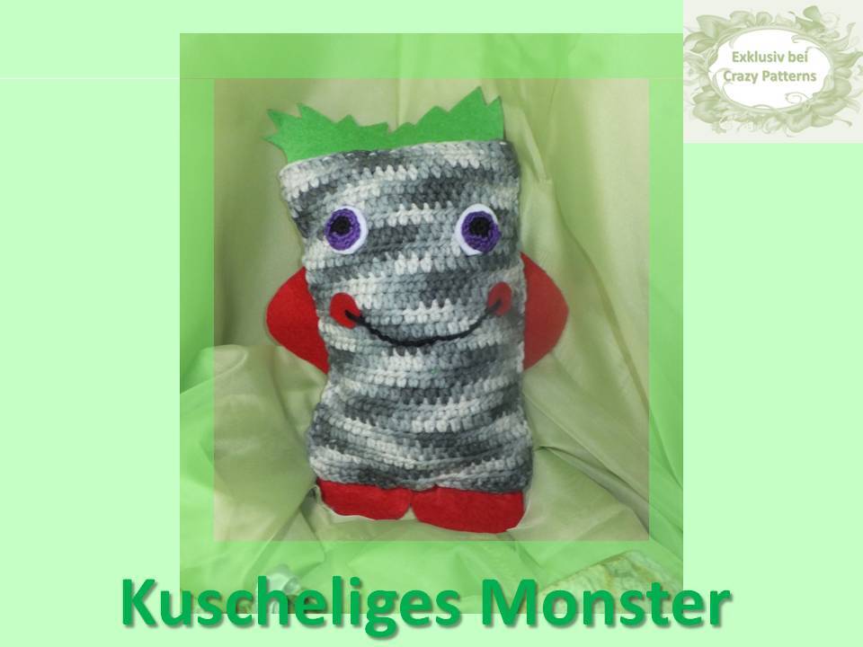 Gehäkeltes rechteckiges Kuschelmonster-Kissen, grau-weiße Streifen, lila Augen, rote Filzdetails, grüne Zacken