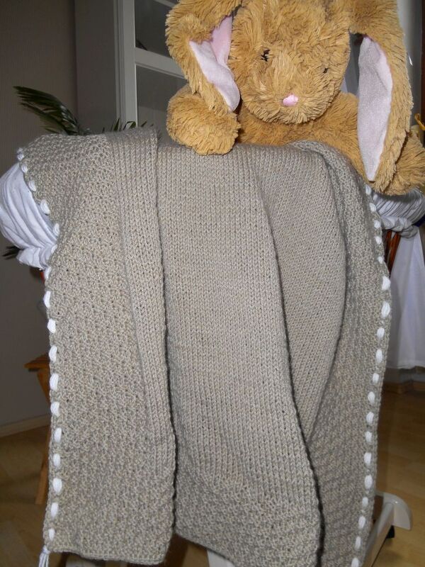 Beige gestrickte Babydecke mit weißen Noppen und braunem Plüschhasen.