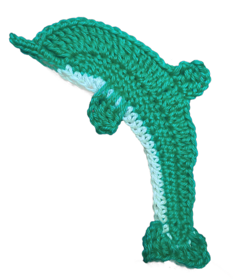 Gehäkelte Delfin-Applikation in Türkis und Weiß vor hellem Hintergrund