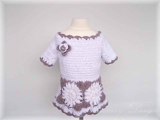Gehäkeltes Kinderkleid in Weiß und Grau mit Blumenapplikationen auf einem Mannequin