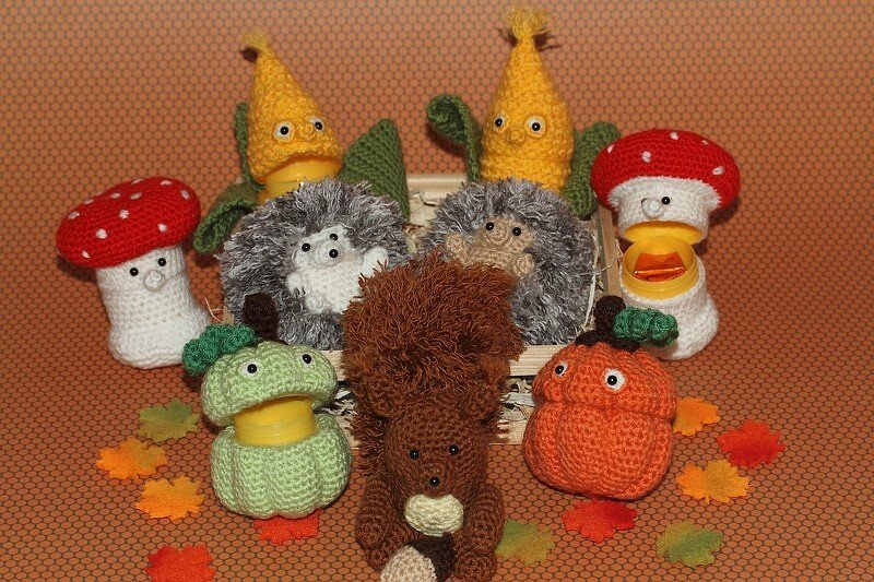 Gehäkeltes Amigurumi-Herbstset mit zwei Igeln, einem Eichhörnchen, Fliegenpilzen, Maiskolben, Apfel und Kürbis, teils als kleiner Behälter