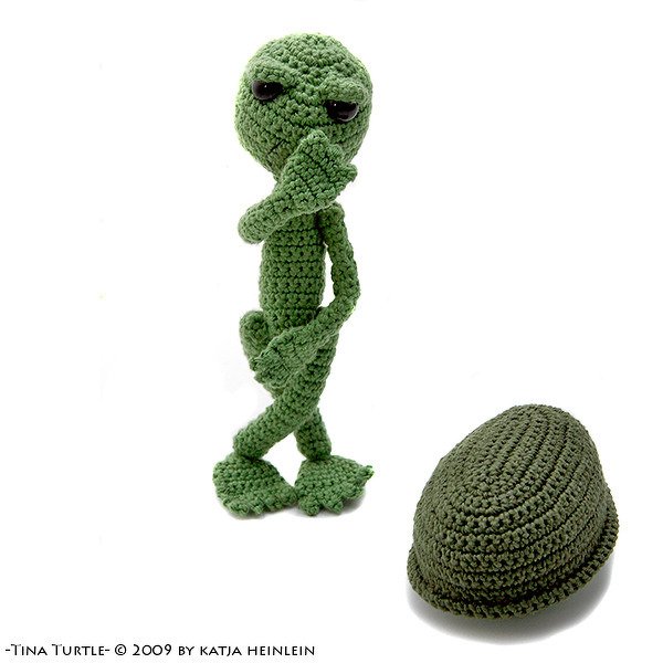 Green crocheted turtle amigurumi standing with removable shell on white background