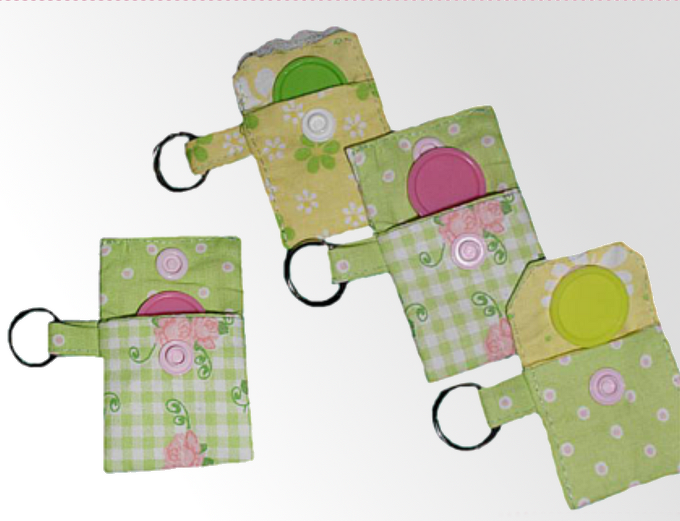 Vier kleine genähte Täschchen aus grün-gelbem Baumwollstoff mit rundem Kunststoffeinsatz und Schlüsselring