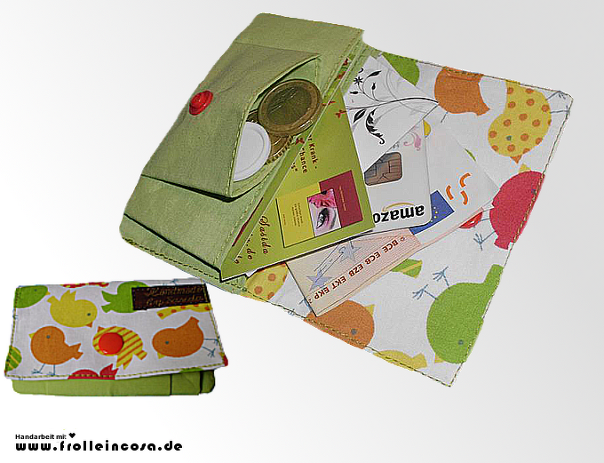 Grüne Stoff-Geldbörse mit buntem Vogelmuster, geöffnetes Innenfach mit Münzen, Karten und Druckknopfverschluss