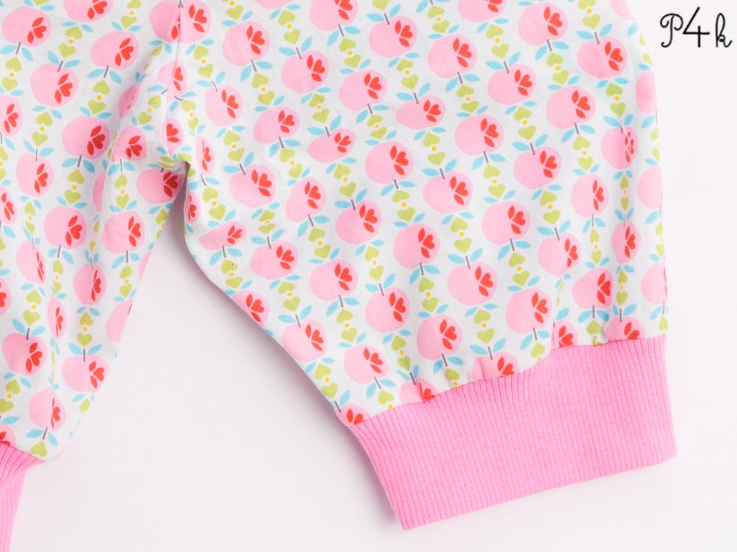 White fabric with repeating pink fruit and floral pattern and pink rib knit cuff