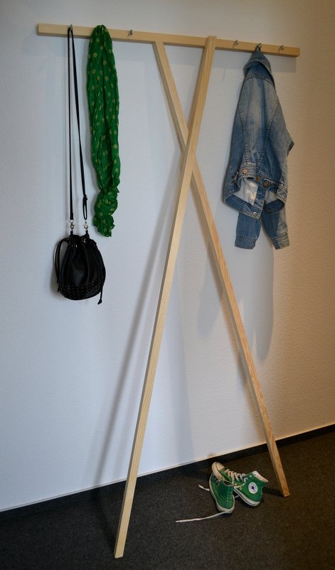 Holzgarderobe im X‑Design mit Hakenleiste, Tasche, Schal und Jeansjacke