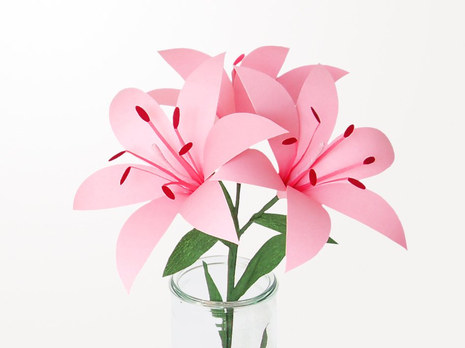 Drei rosa Papierlilien mit grünen Papierstielen in Glasvase