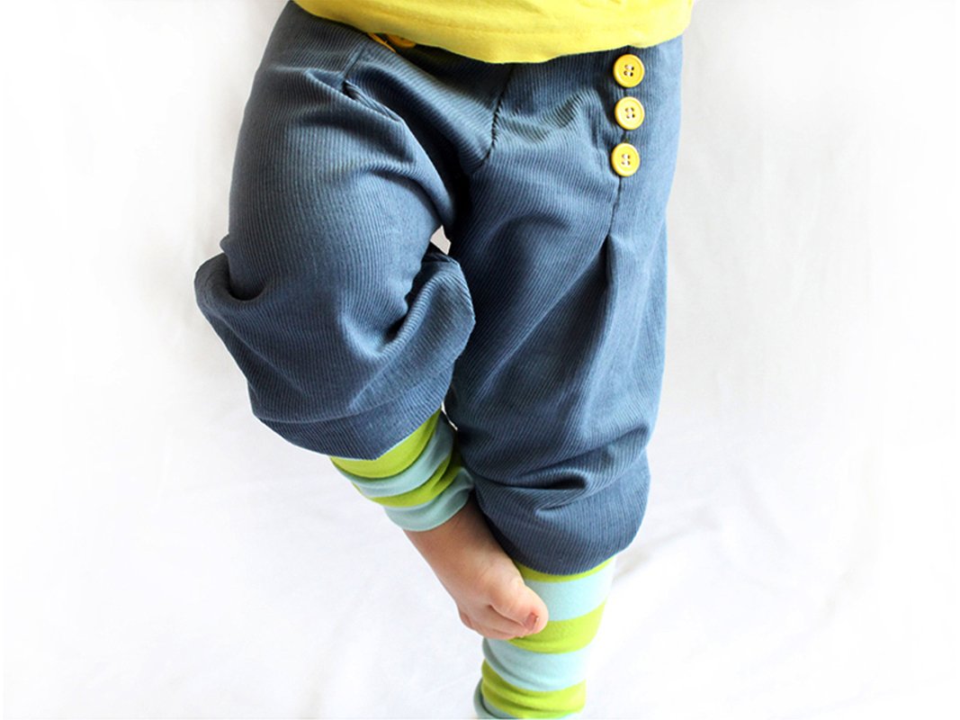 Kinderhose aus blauem Rippstoff mit drei gelben Knöpfen und gestreiften grünen-hellblauen Leggings