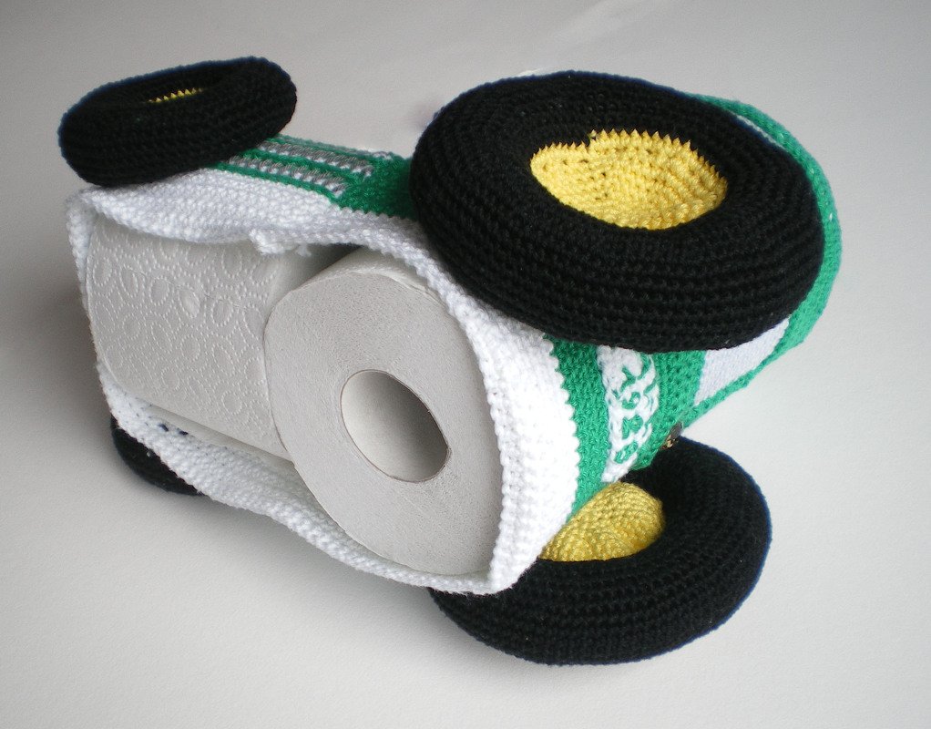 gehäkelte Toilettenpapier-Hülle in Form eines grünen Autos mit schwarzen Rädern und sichtbarer WC-Rolle