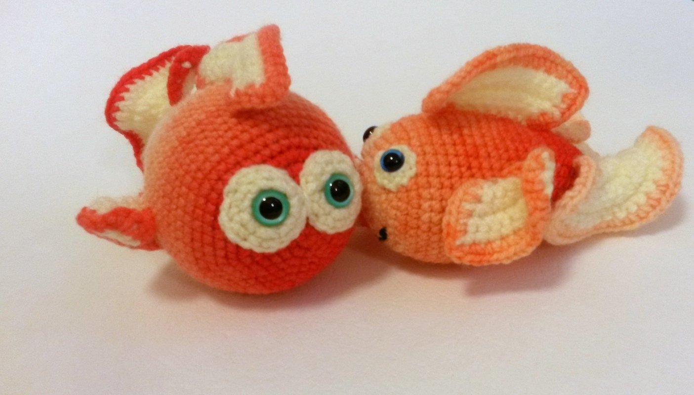 Zwei gehäkelte orange-weiße Goldfische mit großen Augen und sichtbaren Maschen