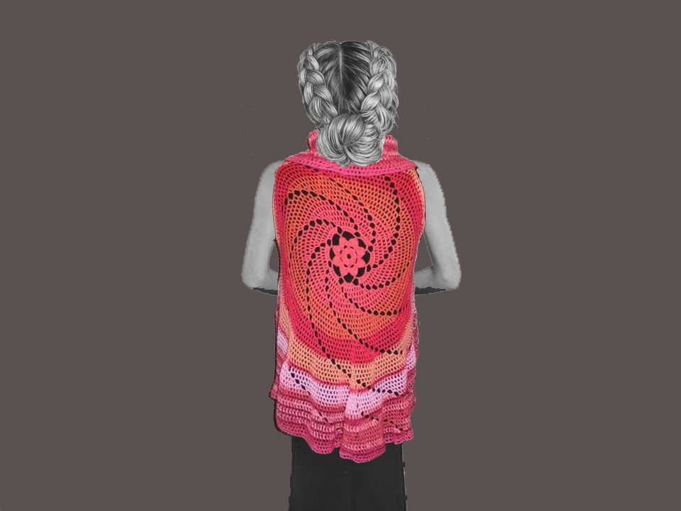 Rückansicht einer Person mit geflochtenen Haaren, die eine bunte, gehäkelte Weste mit großem Spiralmuster und Rüschen am Saum trägt.
