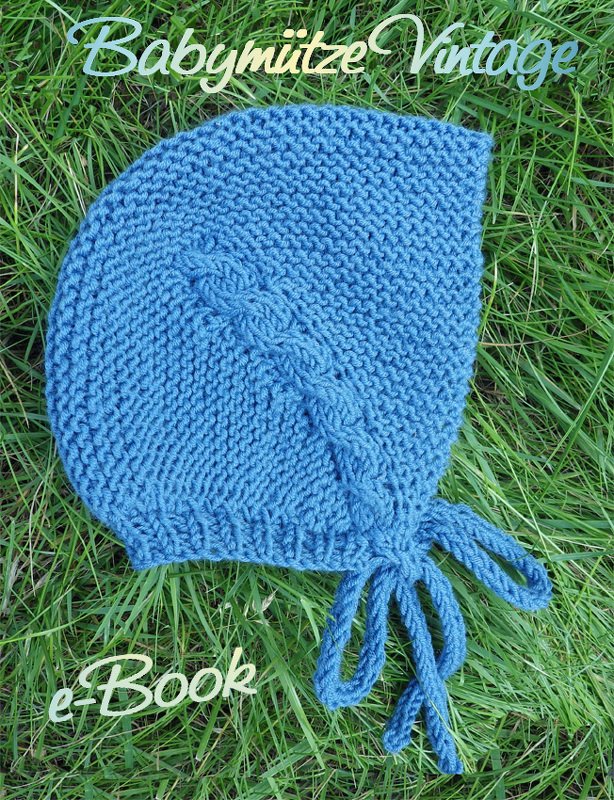 Blaue gestrickte Babymütze mit Zopfmuster auf Gras