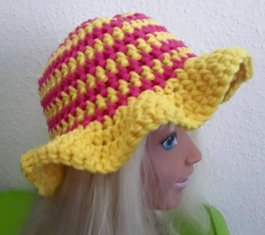 Gehäkelter gelb-pinker Hut mit welligem Rand auf einer Schaufensterpuppe