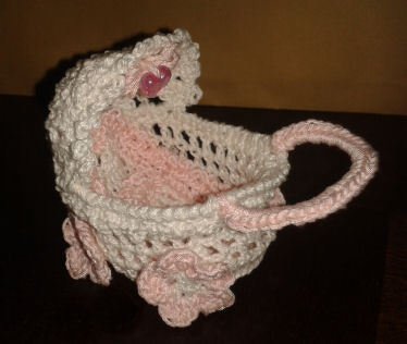 Gehäkelter Babywagen aus rosa-weißem Garn mit Haube und Blumen