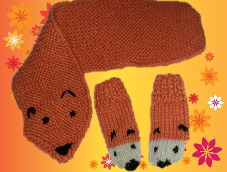 Gestricktes orangefarbenes Fuchs‑Set mit Schal in Fuchsform und zwei passenden Fäustlingen vor gelbem, floral dekoriertem Hintergrund.
