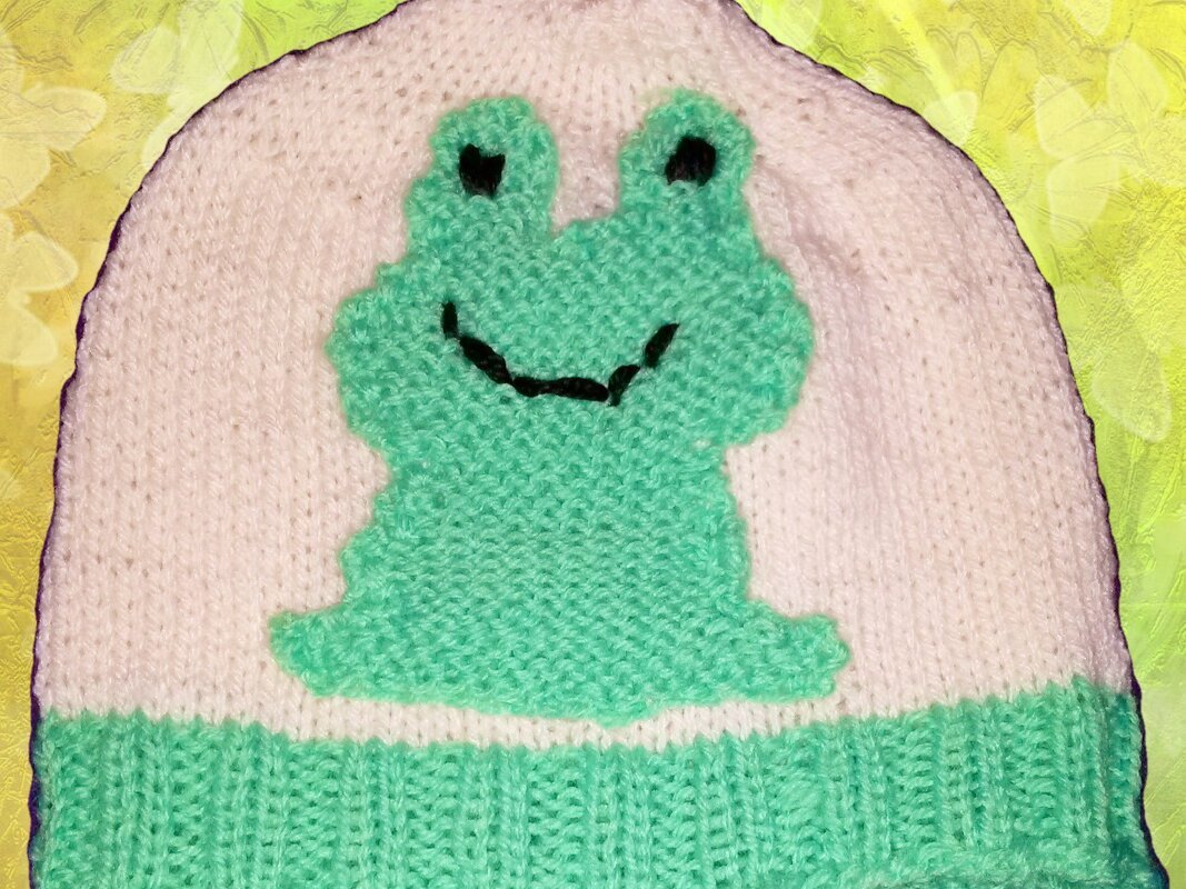 Cremeweißes gestricktes Kinder-Mützchen mit mintgrünem Froschmotiv und Rippbündchen