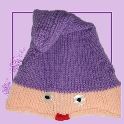 Gestrickte Kindermütze in Lila und Beige mit Knopfaugen und rotem Mund