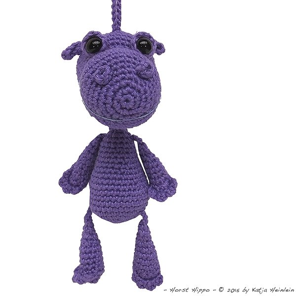 Lila gehäkeltes Amigurumi-Nilpferd mit Schlaufe vor weißem Hintergrund