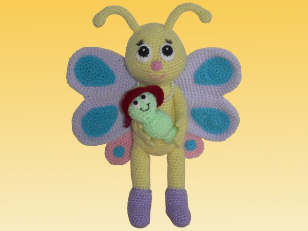 Gehäkeltes gelbes Schmetterlings-Amigurumi mit lila und türkisen Flügeln, hält eine mintgrüne Raupe