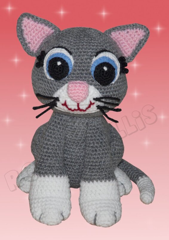 Gehäkelte grau-weiße Amigurumi-Katze mit blauen Augen und rosa Details vor rosafarbenem Hintergrund.