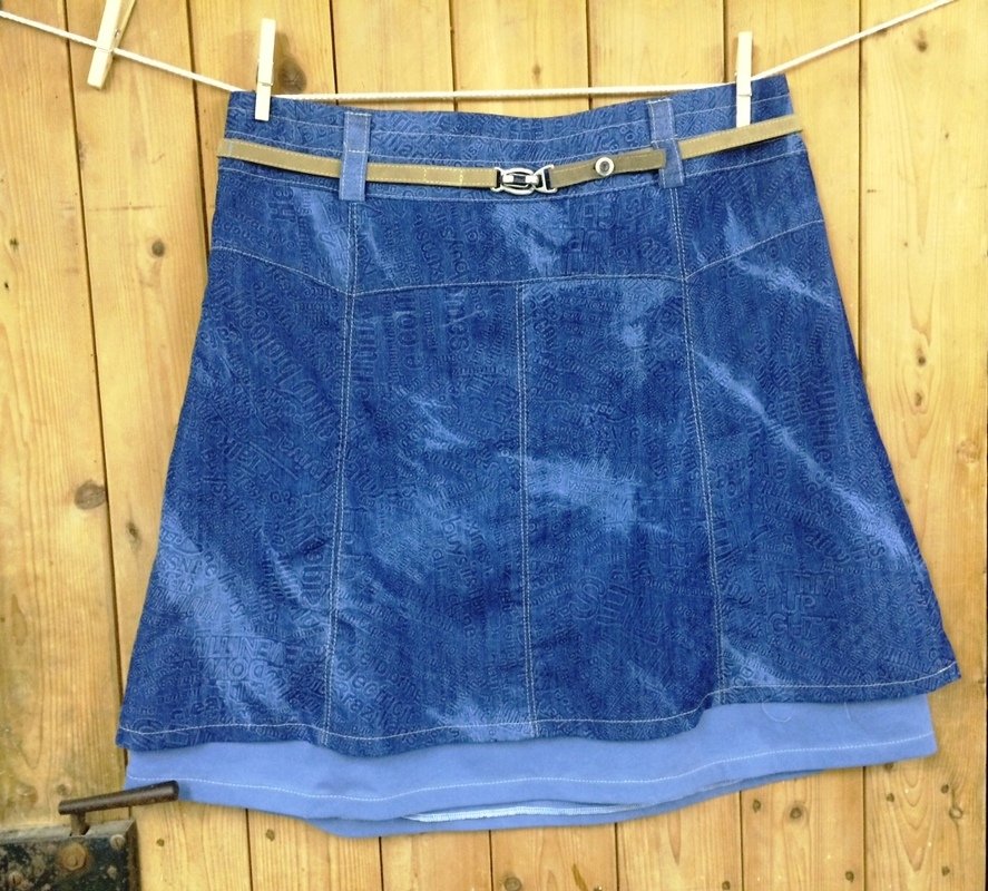 Blauer A-Linien-Rock mit Textmuster und braunem Gürtel an Wäscheleine