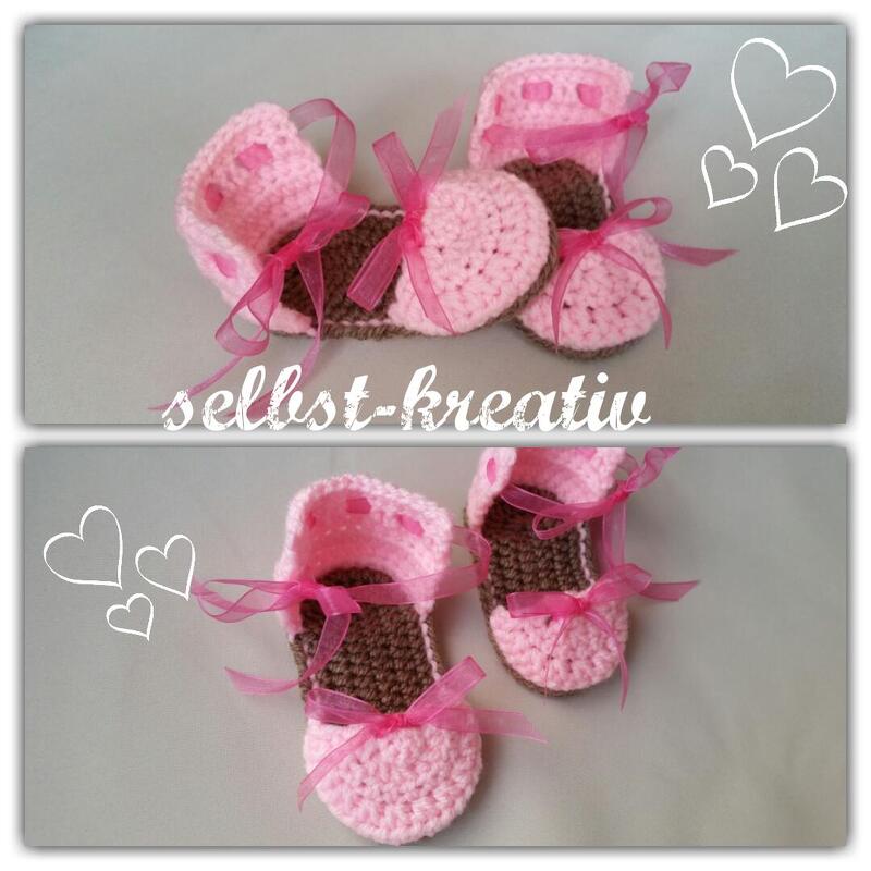 Zwei Paar rosa-braune gehäkelte Babyschuhe mit rosa Schleifen auf neutralem Hintergrund