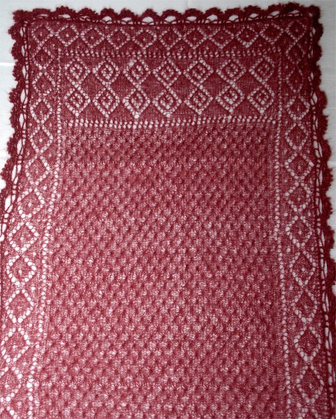 Rechteckiges gestricktes Lacetuch in dunkelrosa mit dichtem Strukturmuster in der Mitte und diamantförmiger Lochbordüre sowie gezacktem Rand