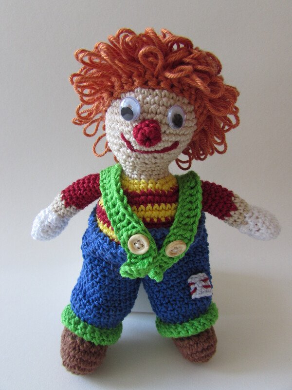 Gehäkelte Clown-Amigurumi mit orangefarbenen Locken und blauer Latzhose