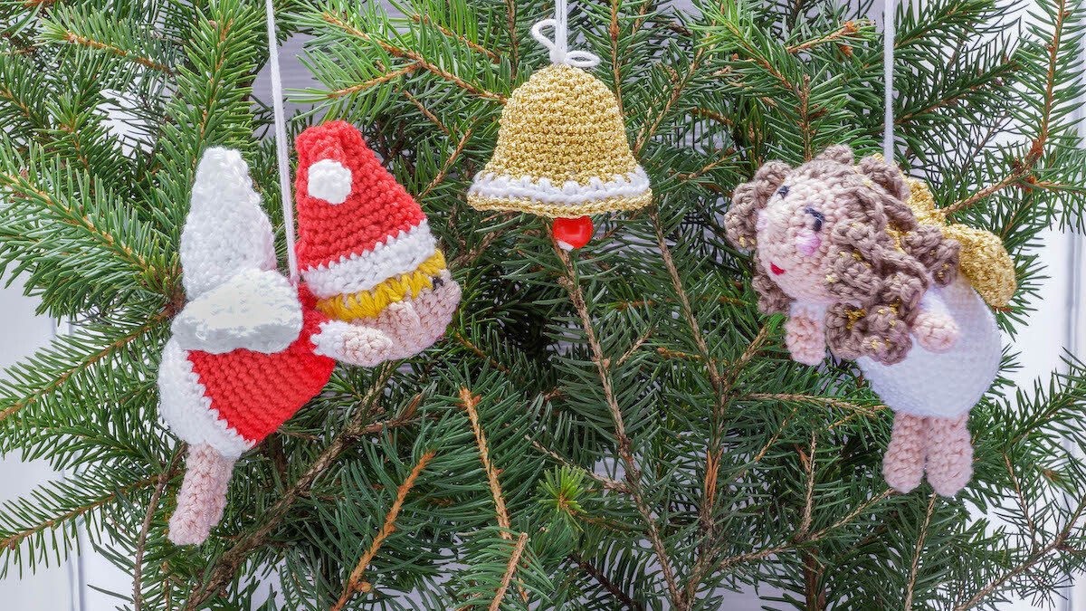Handgehäkelte Weihnachtsanhänger: roter Wichtel, goldene Glocke und lockiger Engel an Tannenzweig