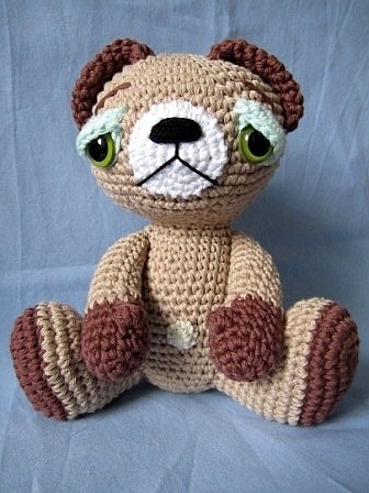 Sitzender gehäkelter Amigurumi-Teddybär in Beige und Braun mit grünen Augen