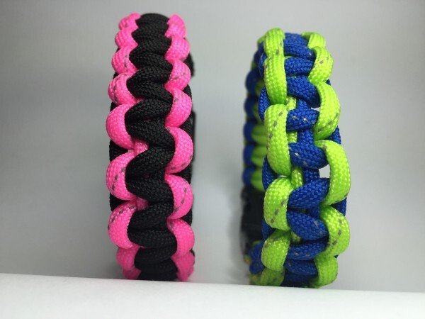 Nahaufnahme zweier geflochtener Armbänder in pink‑schwarz und blau‑neongrün