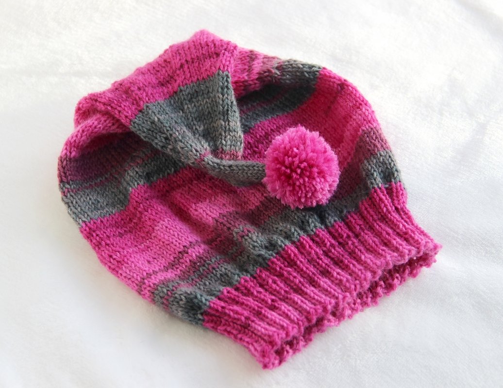 Gestrickte gestreifte Kindermütze in Pink und Grau mit Bommel