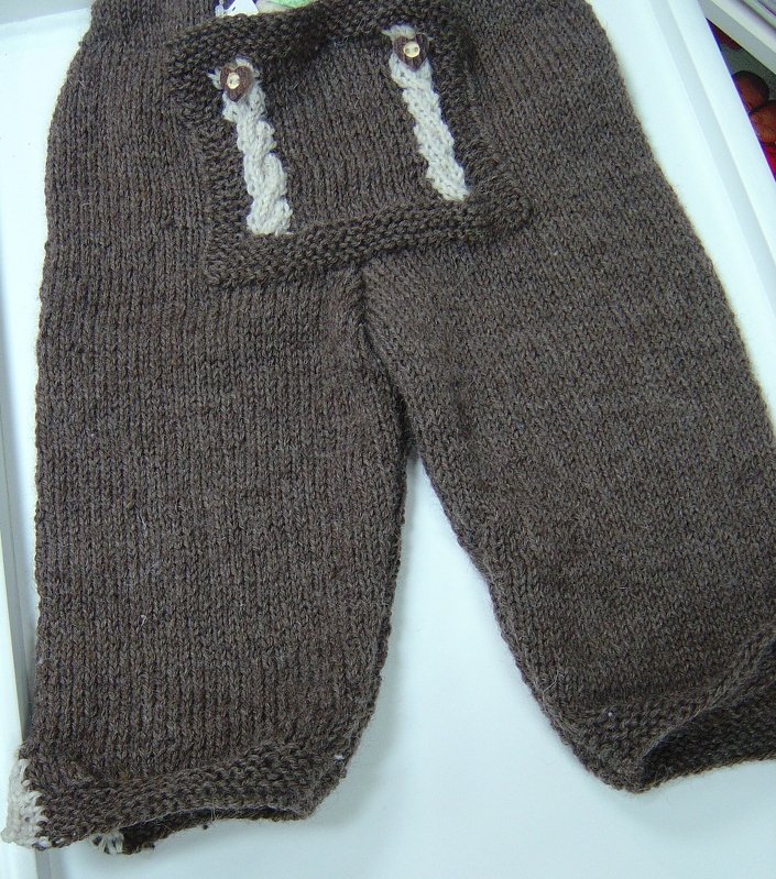 Braune gestrickte Baby-Latzhose mit hellen Zierträgern und Knöpfen